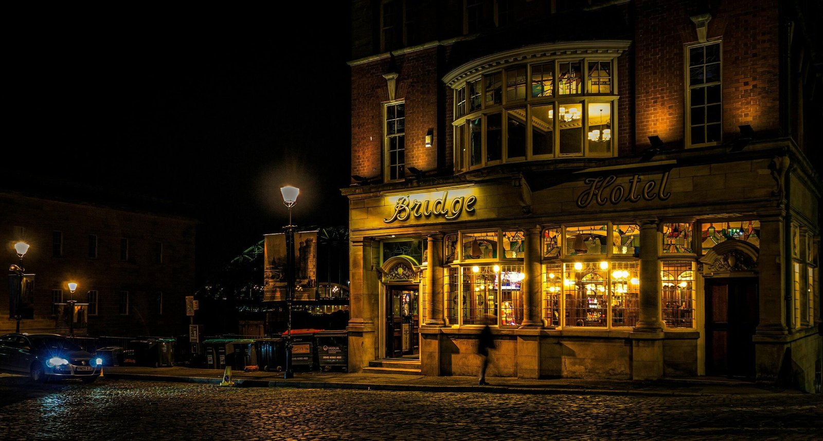 pexels-photo-8409922-8409922 Bridge Hotel in Newcastle upon Tyne illuminated at night, capturing vibrant city life.