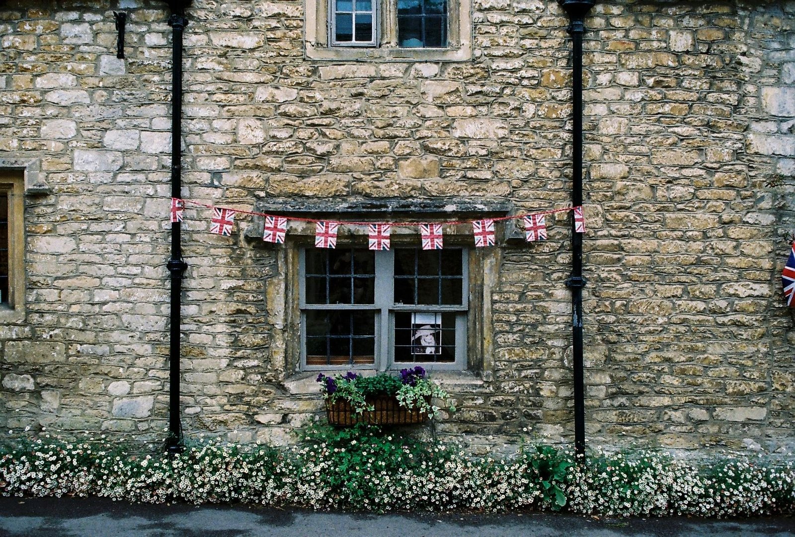 pexels-photo-941227-941227 Rustic stone facade of a traditional British house with flag bunting and flowers.